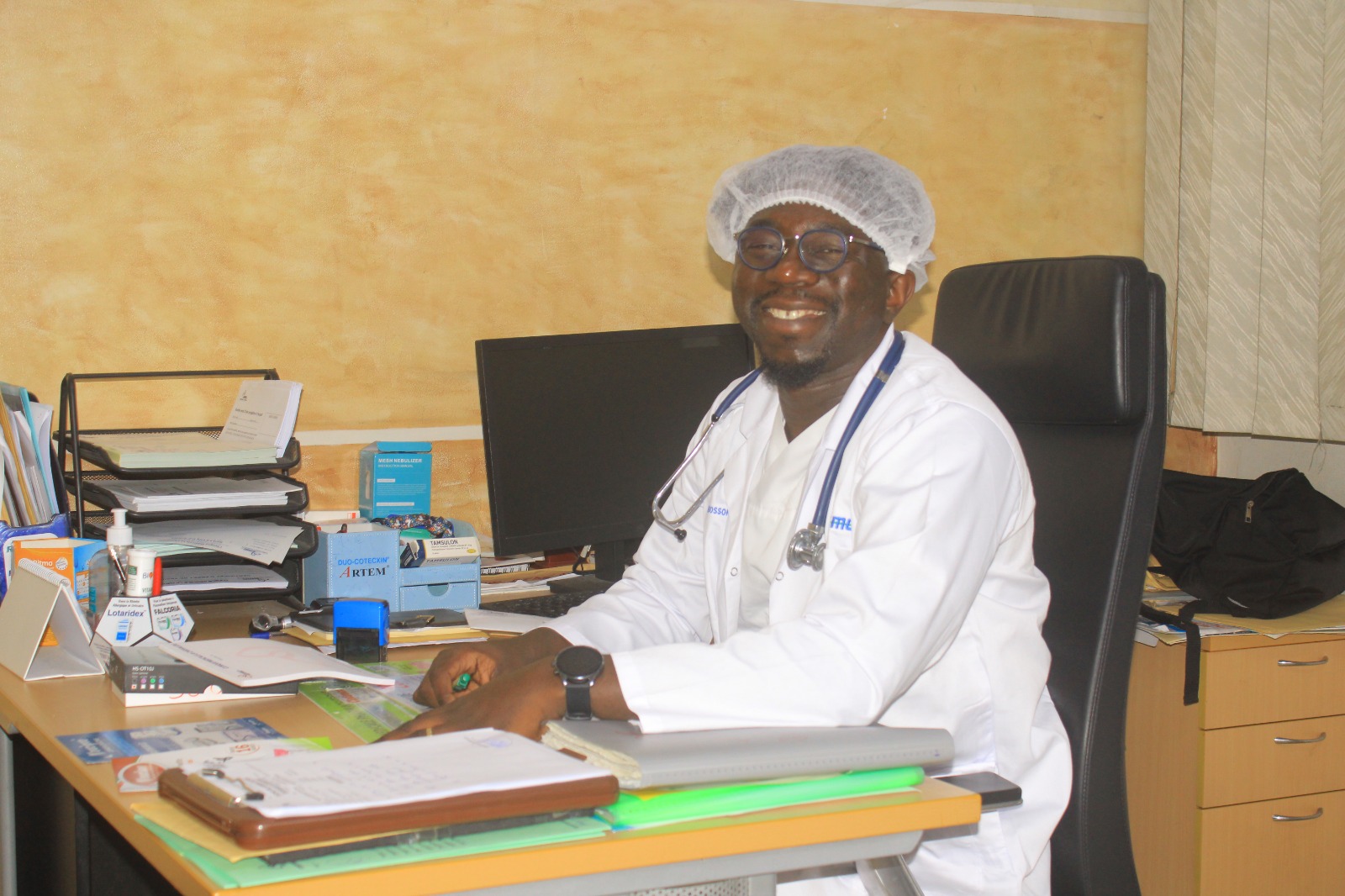 Un médecin généraliste souriant à son bureau de consultation